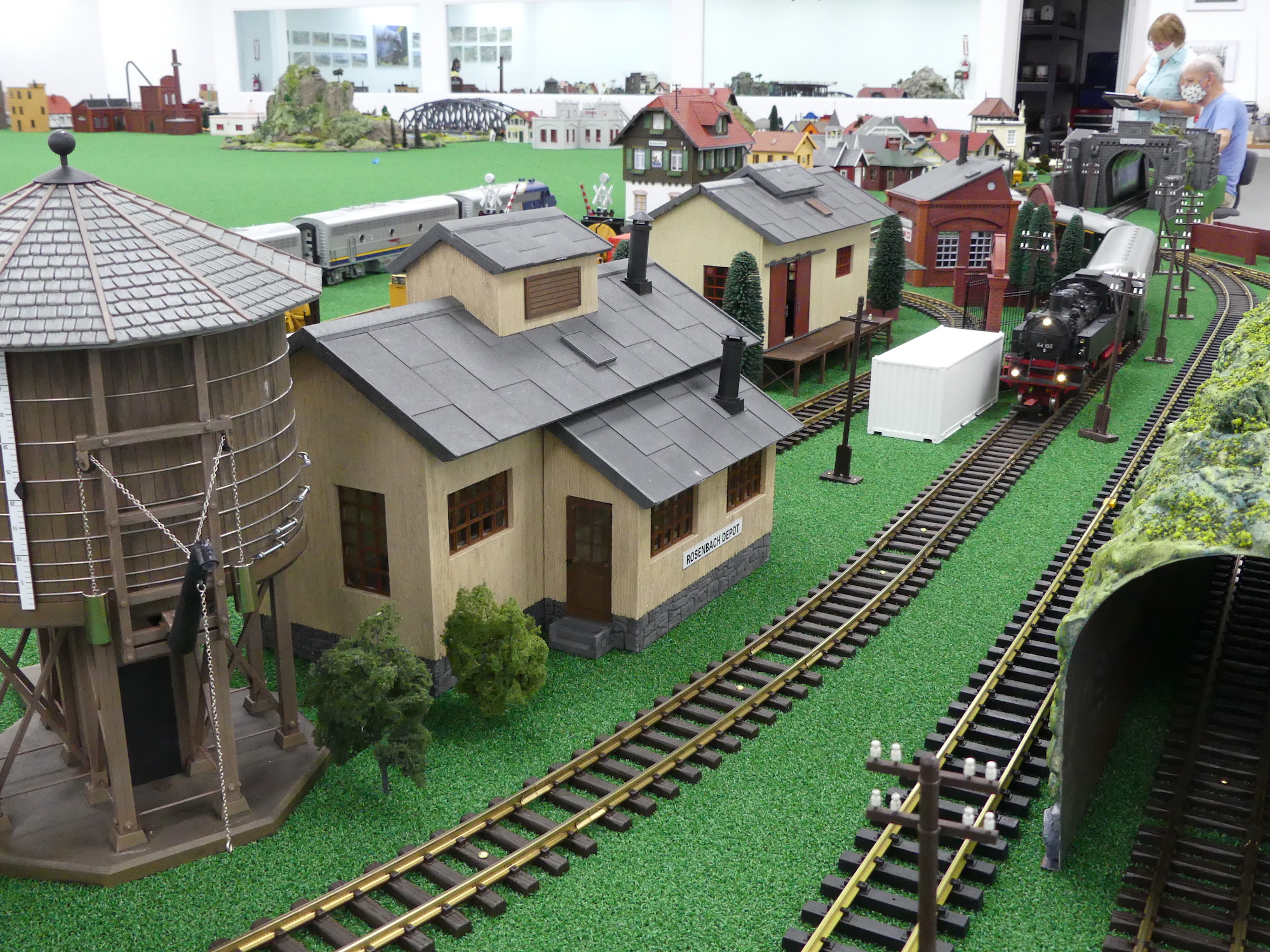 Steam-powered passenger train chugging and smoking through a small town.